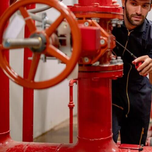 Worker inspecting industrial fire suppression equipment