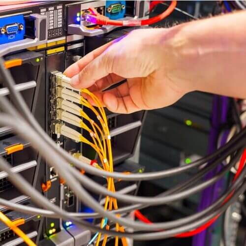 Technician plugs a fiber optic cable into a network
