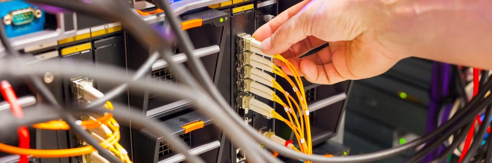 Technician plugs a fiber optic cable into a network