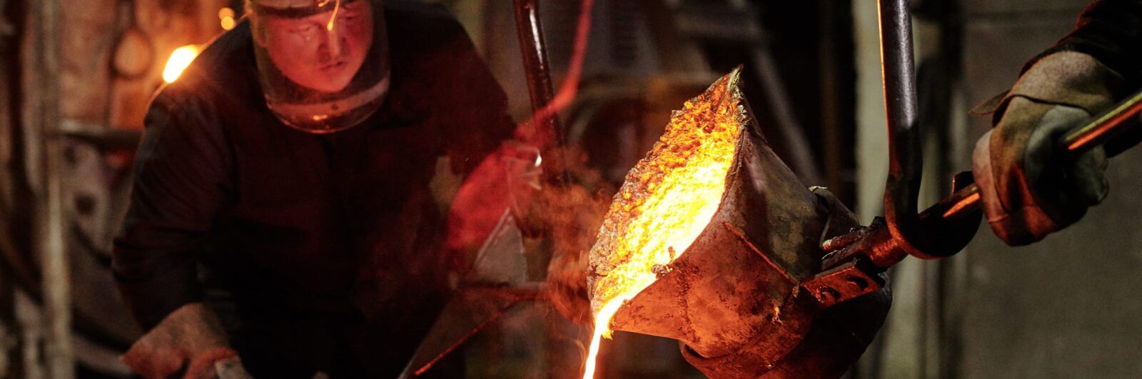 Worker pouring molten metal into a cast
