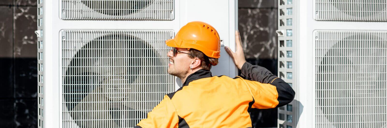 Worker installing air conditioning compressors